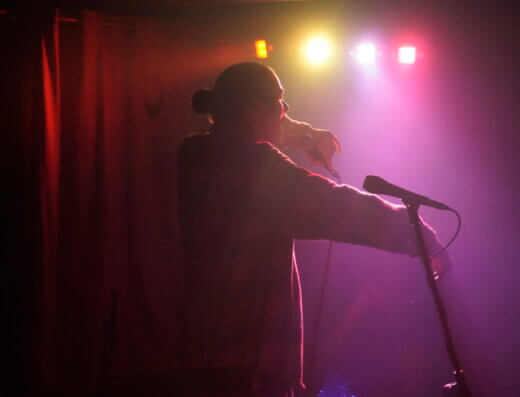 Kingston hip-hop artist, Hartman, rapping into a microphone on stage during performance.